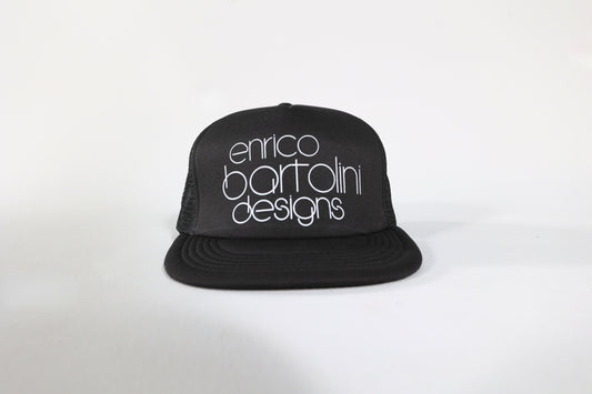 Black cap with 'enrico bartolini designs' text on a white background
