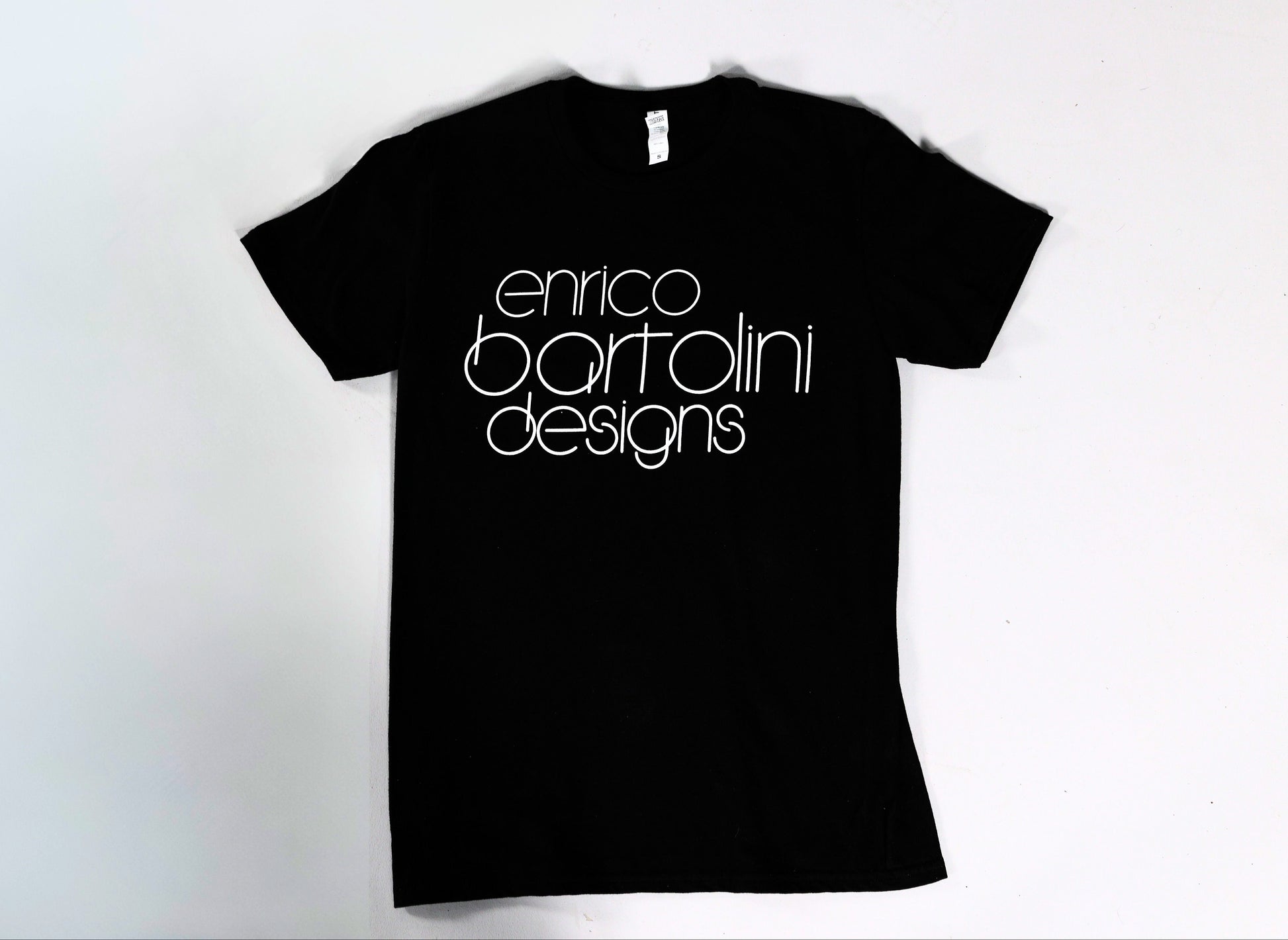 Black t-shirt with 'enrico bartolini designs' text on a white background